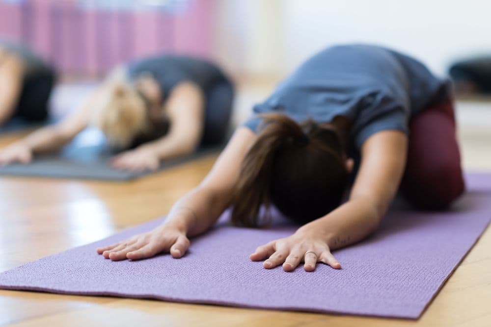 Yoga students resting in child's pose during a class