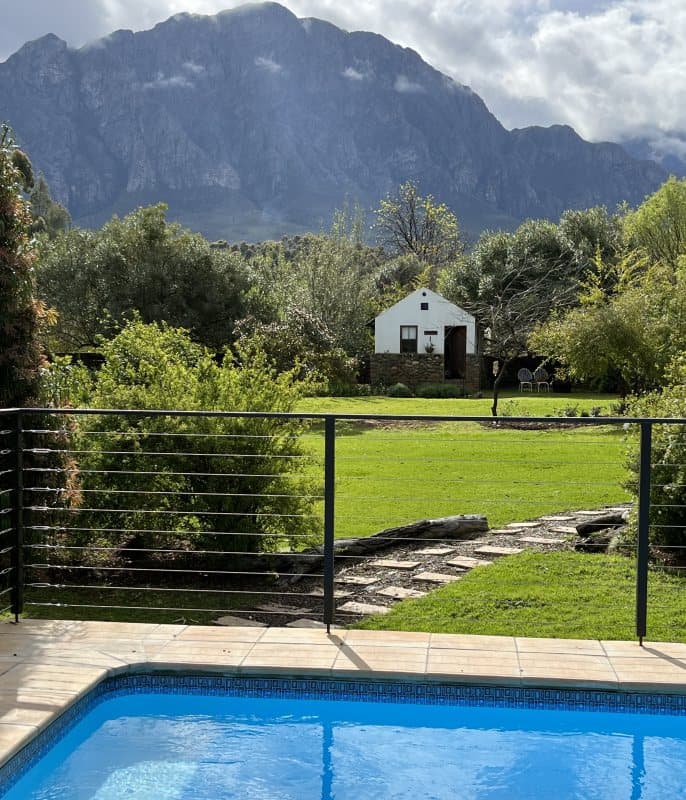 Pool, lawn and white cottage below the Winterhoek Mountains at Welbedacht Nature Reserve, Tulbagh